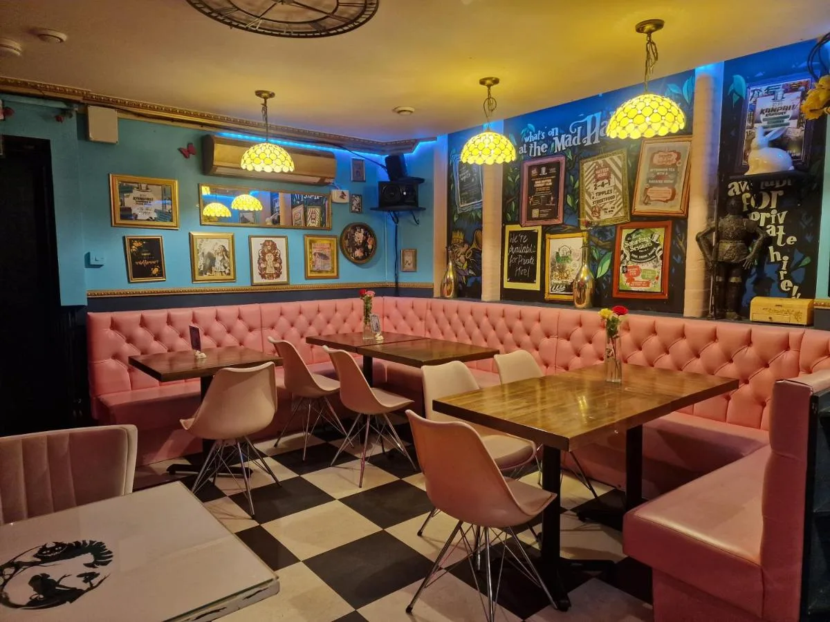 A restaurant with pink booths and tables at The Mad Hatter's Guestrooms in Oxford